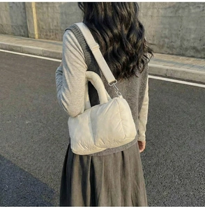 Detail of off-white quilted shoulder bag with adjustable strap and soft padded texture