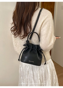 Détail du sac seau noir en cuir avec cordon de serrage et lettrage doré élégant