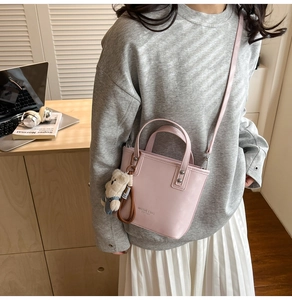 Sac à main en cuir rose pâle porté en bandoulière avec breloque ours et lettres