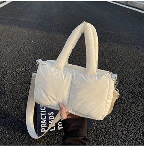 Detail of white quilted tote bag with padded handles and adjustable shoulder strap