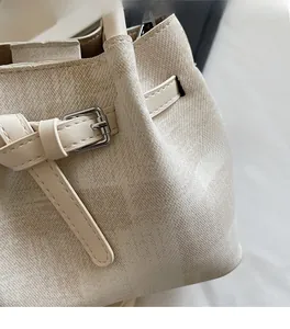 Nahaufnahme der beigen karierten Beuteltasche mit Stofftextur und Silberschnalle