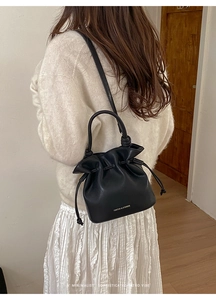 Détail du sac seau en cuir noir mat avec logo blanc et fermeture à cordon coulissant