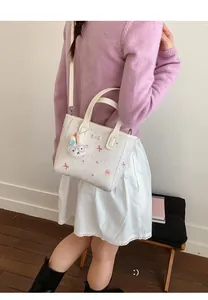 Detail of printed cream bucket bag featuring cute dessert patterns and bunny charm