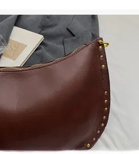 Detail of vintage brown leather crescent bag with gold studs and top zipper closure