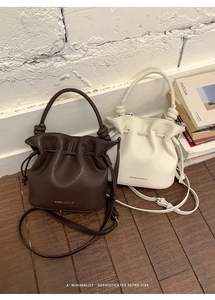 Détail de sacs seaux plissés marron foncé et blanc cassé avec poignées nouées