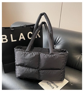 Detail view of the black quilted puffer tote bag on a sofa showing large grid texture