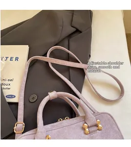 Detail of light purple suede handbag with adjustable strap and gold hardware accents