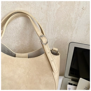 Detail of adjustable strap with silver buckle on beige crescent saddle handbag