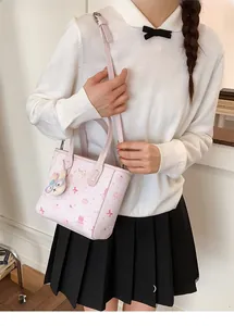 Close-up of pink cartoon bucket bag featuring cute rabbit charm and adjustable strap