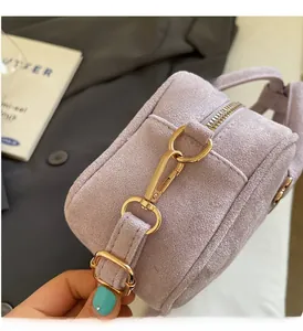 Close-up of golden metal hardware and purple suede texture on a stylish handbag