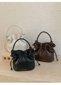 Trois sacs seaux à cordon en beige, marron et noir sur un fond minimaliste chic