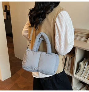 Detail of grey quilted down shoulder bag showing soft puffer texture and shoulder strap