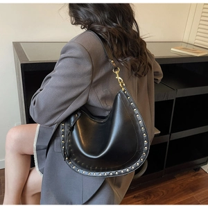 Détails du sac hobo en cuir noir brillant avec des rivets dorés et une bandoulière