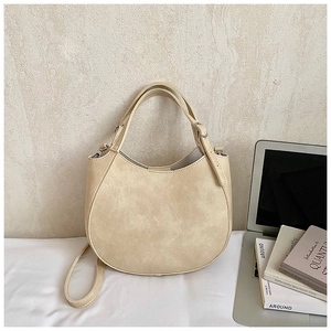 Detail of beige saddle bag with lychee texture and adjustable strap in office setting