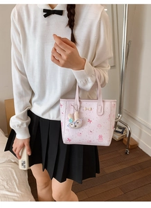 Detail view of pink cartoon embossed handbag with a cute white rabbit plush keychain
