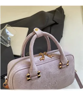 Close-up of lavender suede handbag featuring golden dachshund hardware and smooth zipper