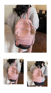 Detail of pink lychee leather backpack with metal logo and plush ball keychain