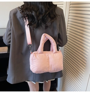 Rear view of a model wearing a pink quilted puffer hobo bag with thick handles