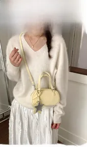 Pale yellow mini crossbody bag with star charm styled with white knit sweater