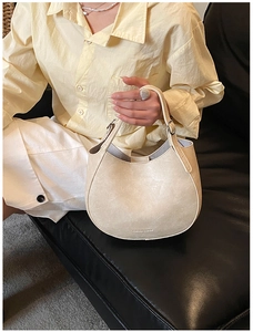 Detail of a beige crescent handbag with smooth matte leather and adjustable silver hardware