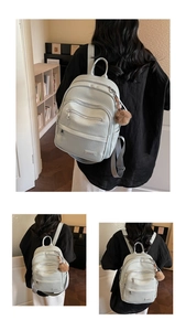 Detail of mint green backpack with lychee texture, multi-zipper and plush ball charm