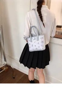 Detail of cartoon print mini tote with adjustable blue strap worn by a model