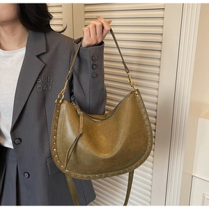 Détail du sac hobo vert olive avec des clous en métal vintage et fermeture à pompon