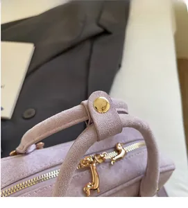 Detail of purple matte baguette bag with dual ring handles and golden dachshund charms