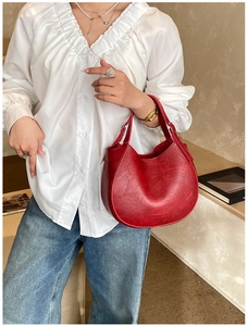 Detail view of red leather moon saddle bag with metal buckle and fashion text
