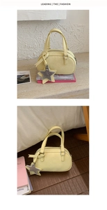 Detail of a yellow shell-shaped handbag with star charm and top handles in a lifestyle setting