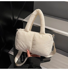 Detail of white quilted puffer tote bag with soft padded handle and silver hardware