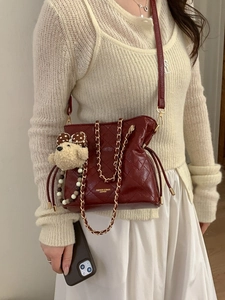 Deep red quilted rhombus chain shoulder bag with cute plush bear pendant on model