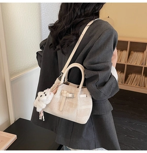 Detailansicht der cremefarbenen Beuteltasche mit Schleife und Plüschkatzen-Anhänger