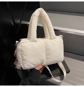 Detail view of cream white quilted puffer tote bag with thick handles and woven strap