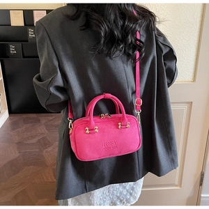 Back view of model carrying a rose pink suede baguette bag with gold metal hardware