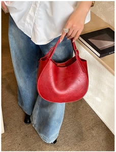 Detailed view of a red crescent saddle bag with vintage leather texture and silver buckle