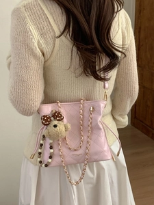 Pink quilted shoulder bag with gold chain and teddy bear charm on model background