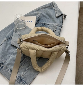 Inside view of beige quilted tote bag showing a zippered pocket and nylon lining