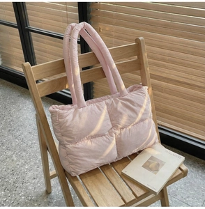 Pink quilted puffer tote bag detail on a wooden chair with soft morning sunlight