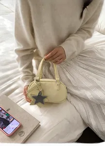 Detail of yellow bowling bag with leather texture and star charm held by model