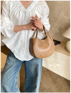 Detailed close-up of a brown leather crescent handbag with Fashion and Bags embossed text