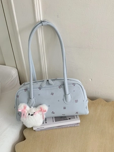 Light blue floral shoulder bag with a teddy bear pendant in a minimalist setup
