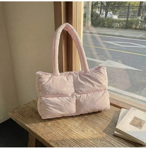 Detailed view of pink quilted puffer tote bag on a rustic bench with soft sunlight