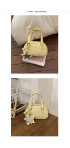 Detail of yellow mini boston bag with star pendant on bed and wooden desk