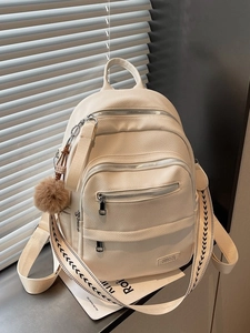 Versatile off-white faux leather backpack with woven strap and decorative pompom charm