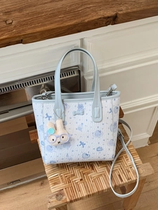 Light blue cartoon print bucket bag with dual handles and adjustable shoulder strap