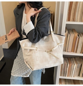 Detail of off-white canvas tote bag with gold hardware and leather shoulder straps