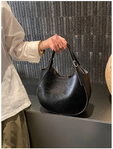 Detail of a black oil-wax leather hobo bag with subtle texture and embossed logo