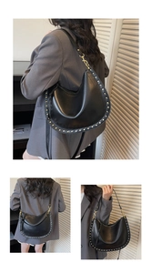Detail of black matte leather saddle bag with gold stud trim and metal buckle accents