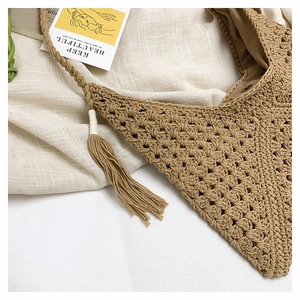 Close-up of woven tote bag showing fringe detail and magnetic clasp on beige fabric